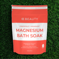 OC Beauty Co. Grapefruit and Spearmint Magnesium Bath Soak in a jar, with fresh grapefruit slices and spearmint leaves beside it.