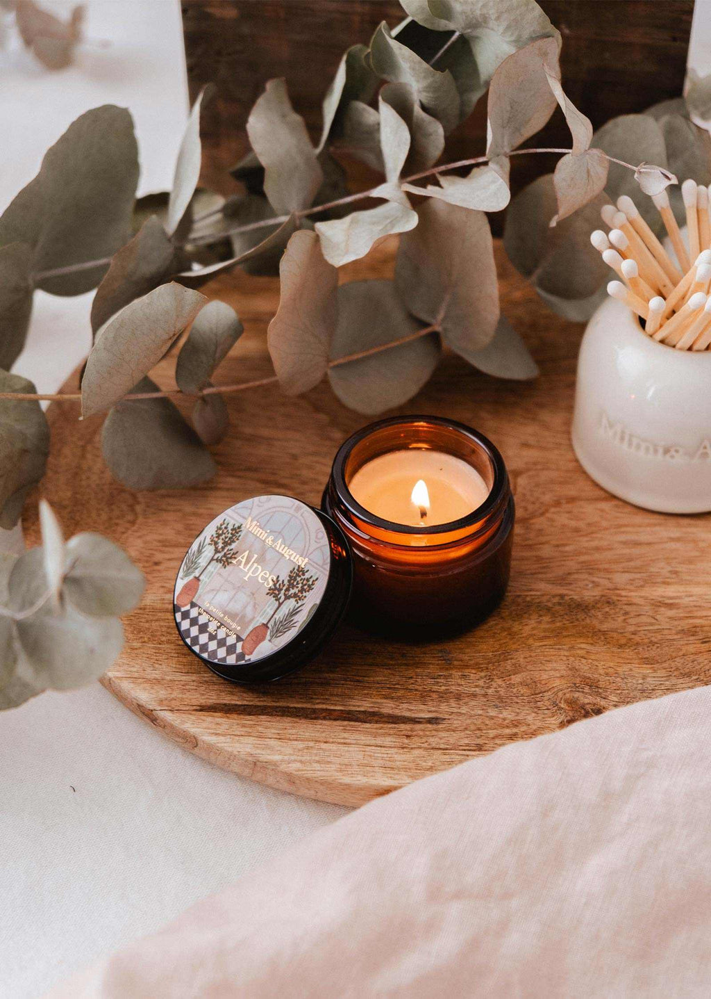 Mini Alpes candle by Mimi & August, 2 oz, featuring a sleek glass container with a soft, inviting candle flame and minimalist design.
