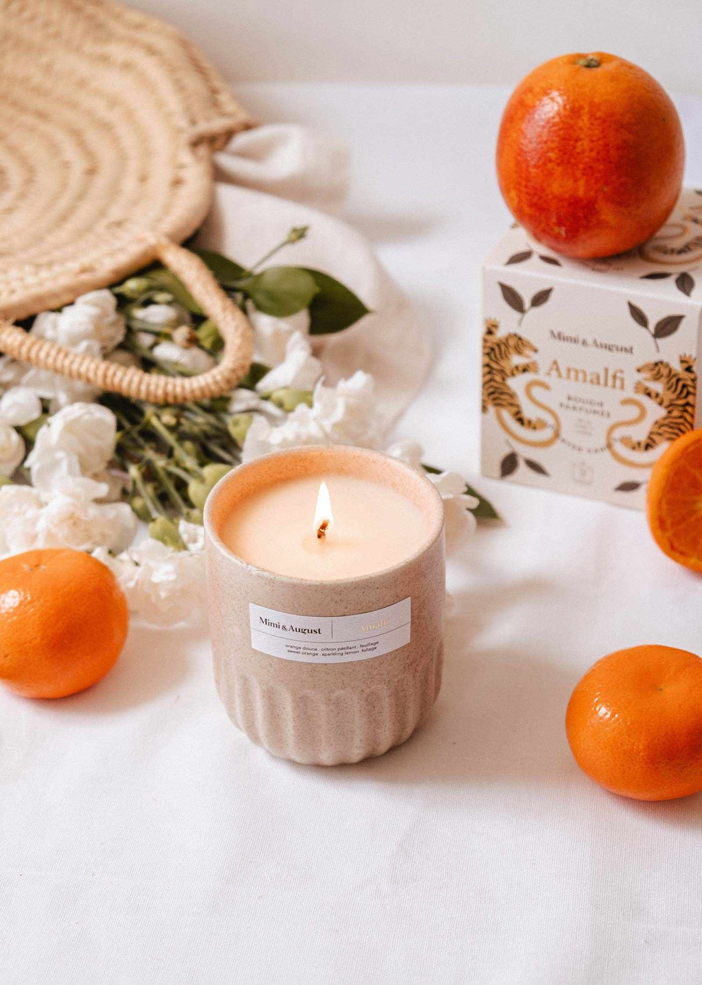 Mimi & August Amalfi reusable candle in an 11 oz glass jar with a lit wick, showcasing a sleek design and warm ambiance.