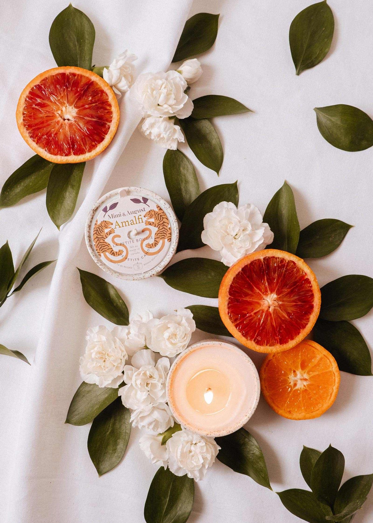 Mimi & August Amalfi reusable 3 oz candle in a sleek glass container with a lit wick and a fresh, citrus-inspired scent.