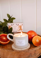 Mimi & August Amalfi reusable candle in a 5 oz glass jar with a lit wick, showcasing a sleek design and soft glow.