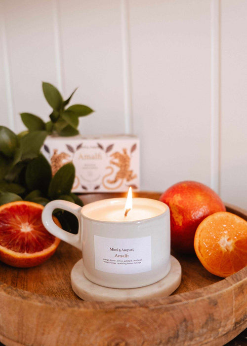 Mimi & August Amalfi reusable candle in a 5 oz glass jar with a lit wick, showcasing a sleek design and soft glow.