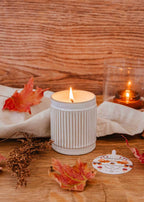 Ambre reusable soy candle by Mimi & August shown in a glass jar with a lit wick, perfect for home decor.