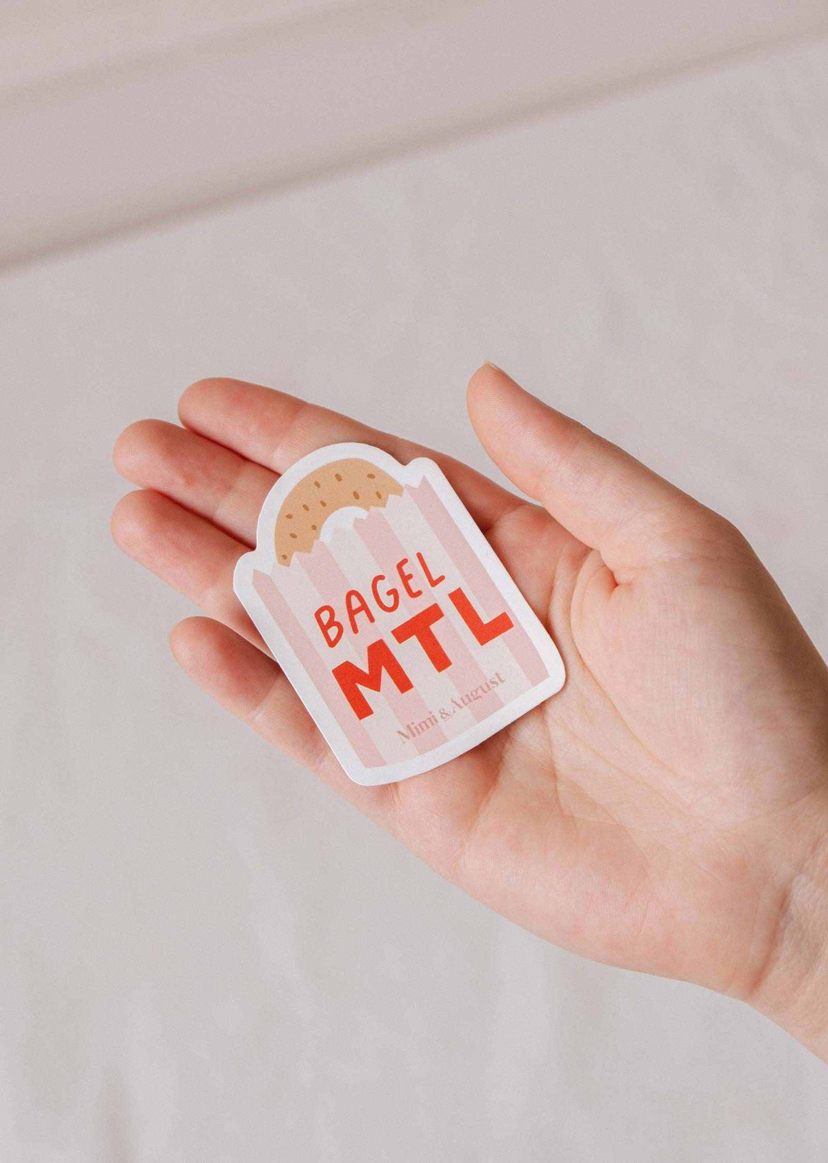 Decorative vinyl sticker of a bagel with "MTL" text from Mimi & August, ideal for customizing laptops or notebooks.