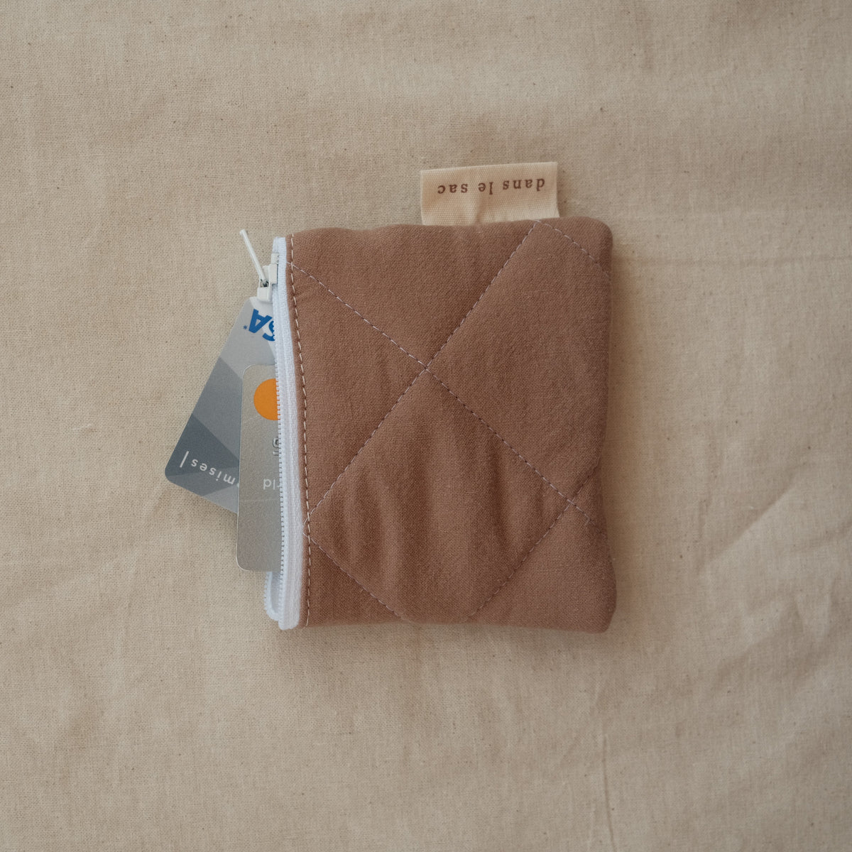 Reusable Dans Le Sac quilted cotton coin purse with a compact, stitched design and soft fabric exterior.