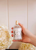 Mimi & August Flores brown ambiance room spray bottle with floral design on a neutral background