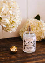 Brown ambiance room spray Flores by Mimi & August, with a sleek bottle and floral accents, ideal for adding subtle fragrance.