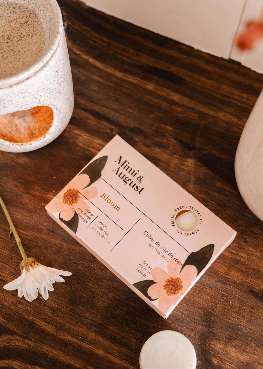 Soy wax melts in Bloom scent by Mimi & August, showing colorful wax tarts with floral packaging and a blooming flower design.