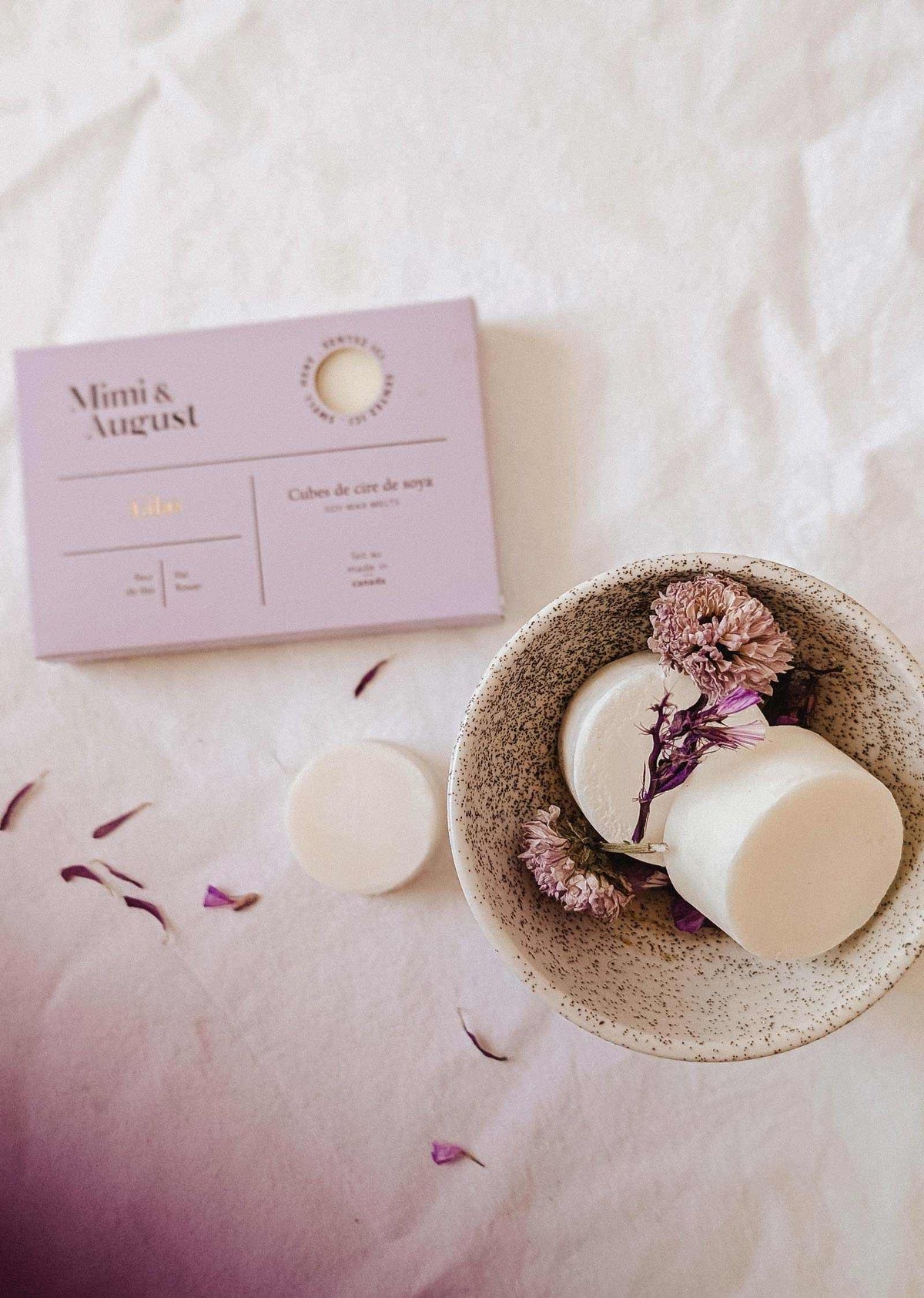 Soy wax melts in lilac color, Mimi & August wax tarts with floral scent, displayed in a clear container on a neutral background.