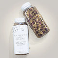Pure Wash Botanical Tea Bath additive in a clear plastic bottle with a white cap, showcasing herbal tea ingredients for relaxing baths.