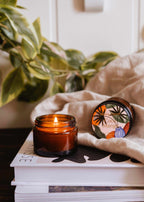 Mini Coco Mango soy candle by Mimi & August in a 2 oz glass jar with a lit wick, showcasing the tropical fragrance.