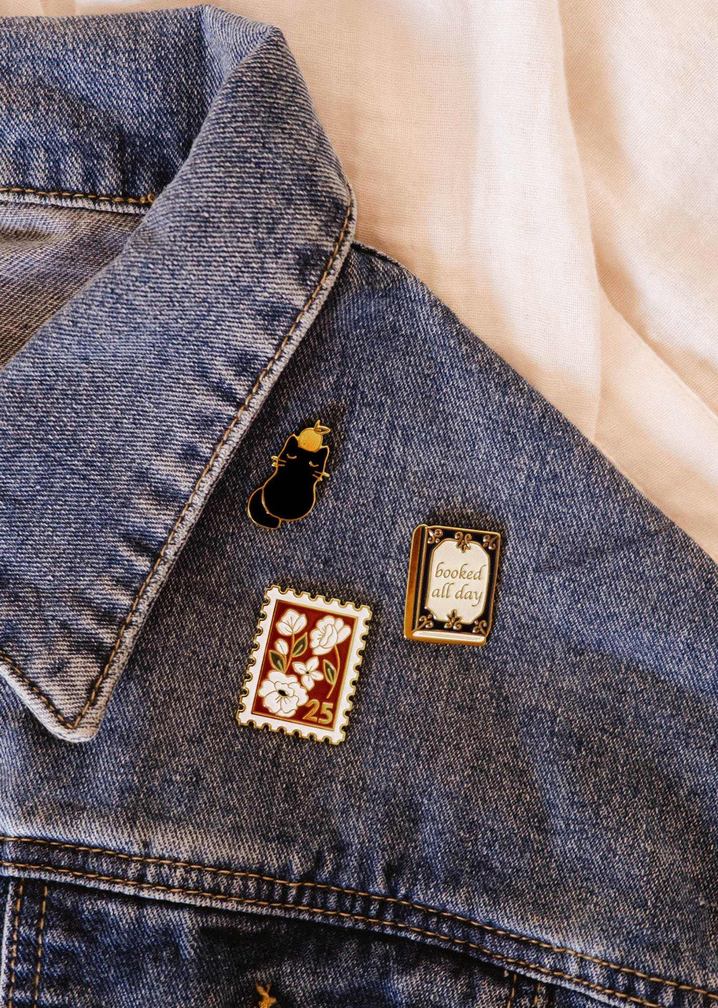 Cute enamel pin featuring a "Booked All Day" design by Mimi & August, shown on a white background.
