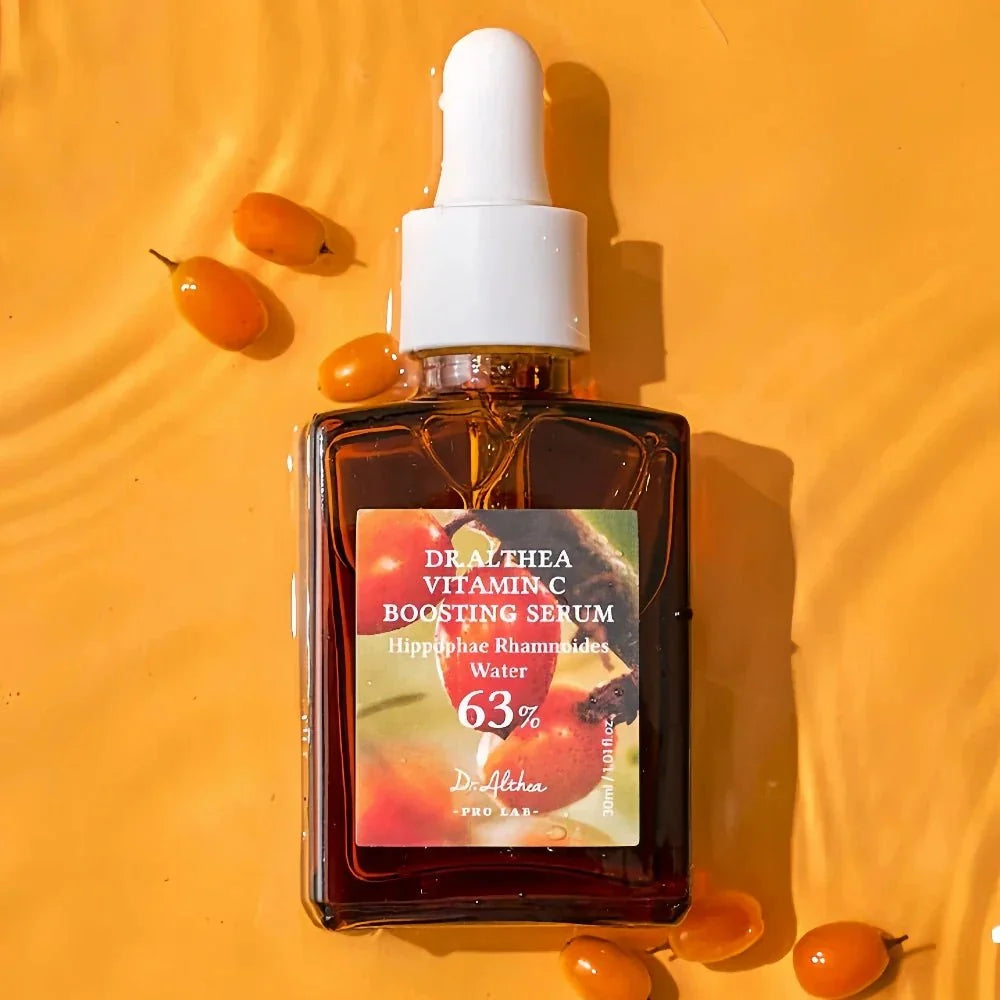 Lakinza Dr. Althea Vitamin C Boosting Serum 30ml in a clear bottle with a dropper applicator, showcasing bright orange liquid.