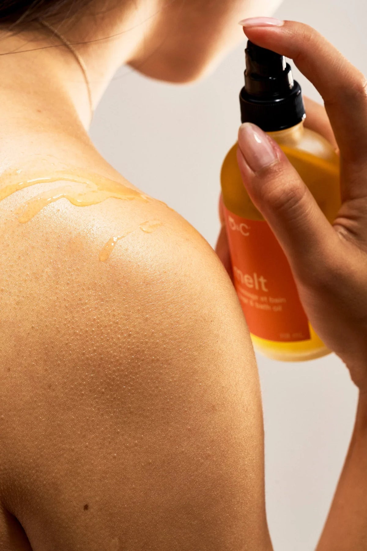Peach and Cream melt massage and bath oil bottle with a relaxing spa setting and soft, soothing lighting.