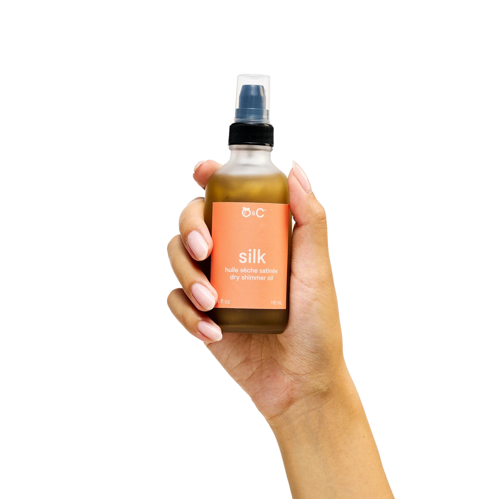 Peach and Cream® shimmer dry body oil with silk, featuring a sleek bottle and luxurious golden shimmer on a soft background.