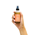 Peach and Cream® shimmer dry body oil with silk, featuring a sleek bottle and luxurious golden shimmer on a soft background.
