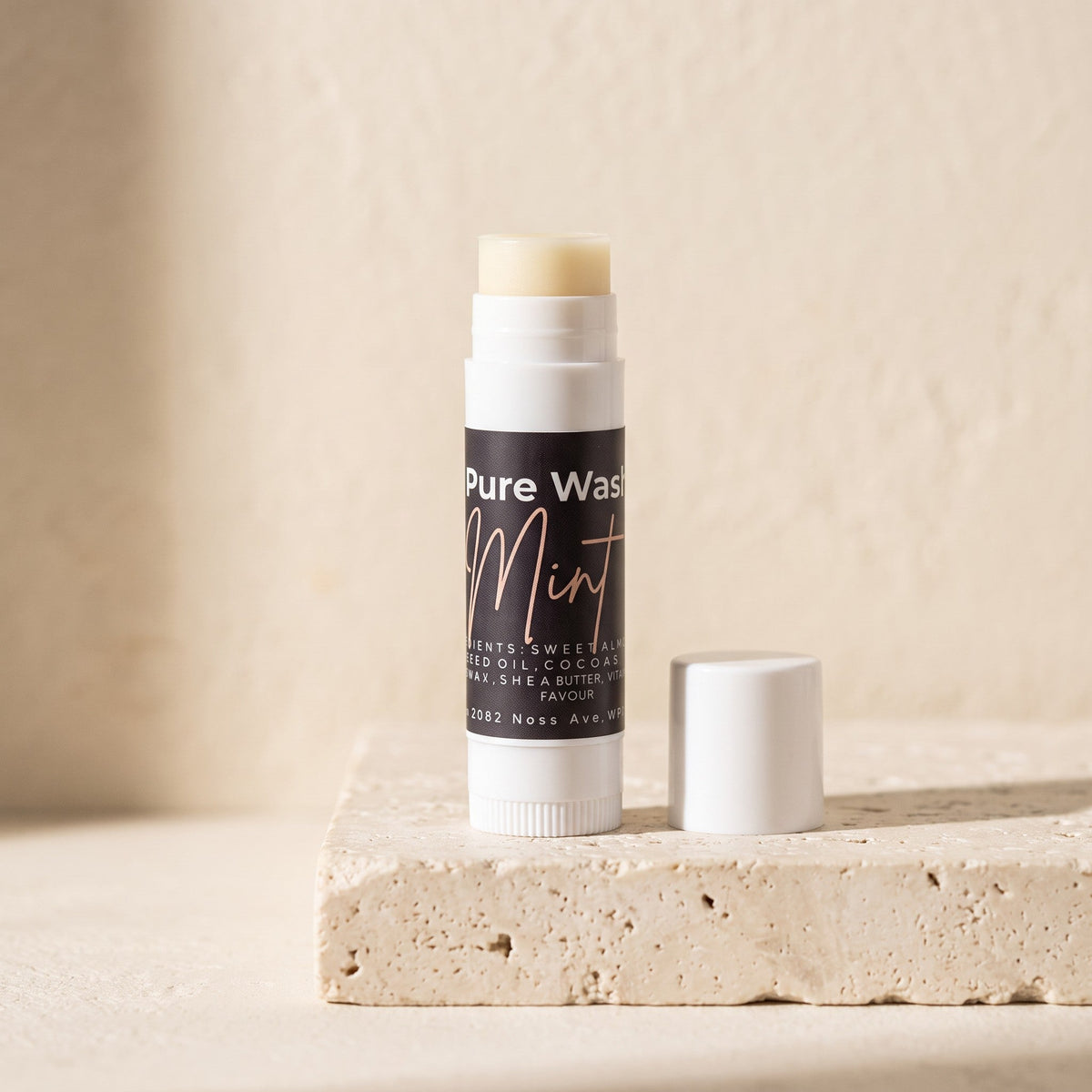 Pure Wash mint lip balm tube with a smooth, shiny surface and a white cap, showing the product label on a plain background.