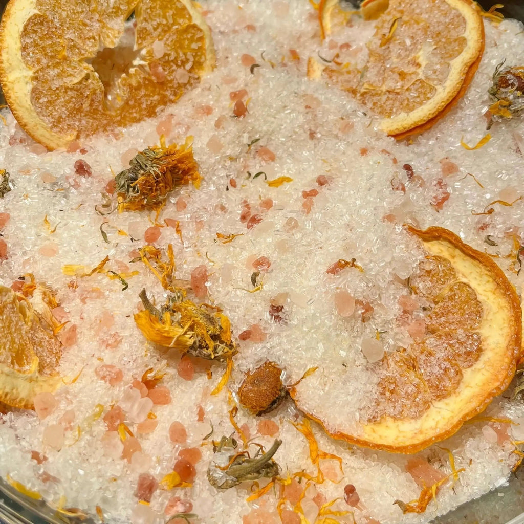 Sunny orange and calendula bath salts from La Sultana Savonnerie, natural handmade bath salts in a clear jar with a bright background.